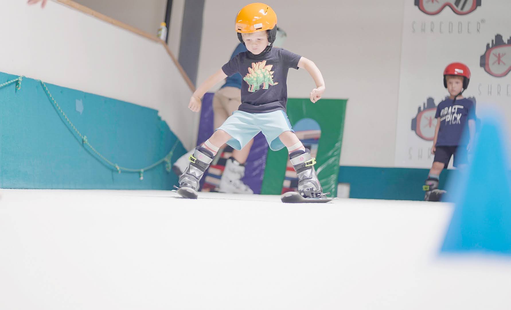 Child skiing indoors at Shredder with instructor coaching