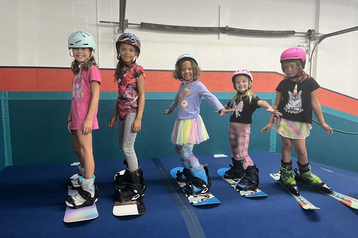 Five girls lined up on their own snowboards and skis at Shredder Livonia