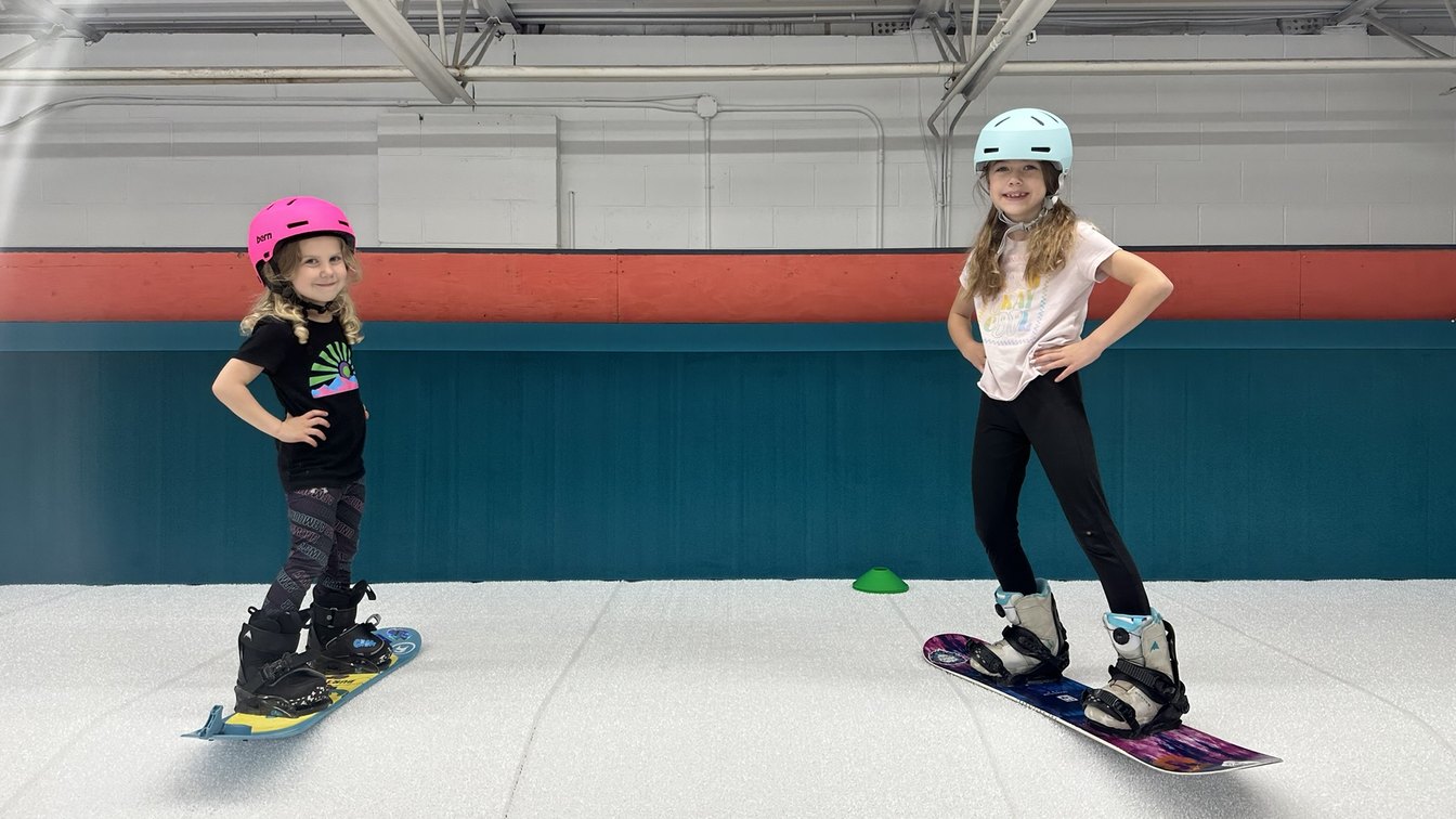 Two young riders standing on their snowboards on the indoor slope at Shredder Livonia