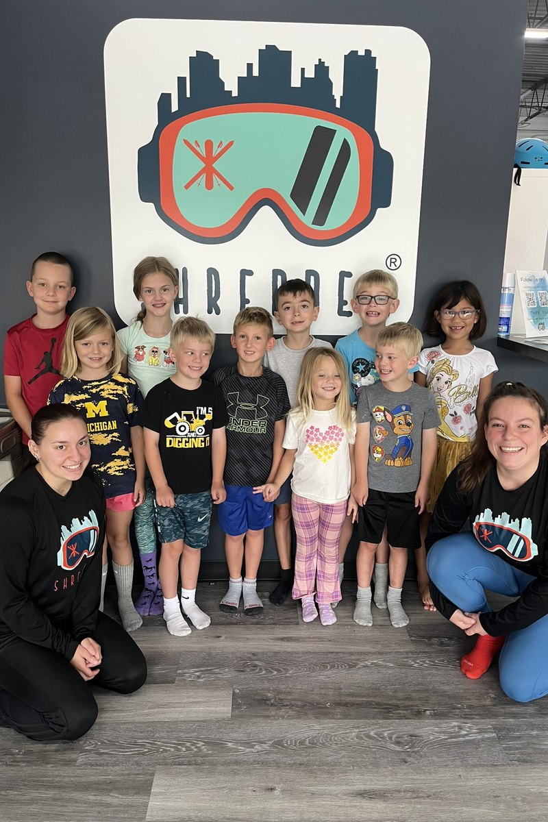 A group of children with two coaches under the Shredder logo at Shredder Livonia