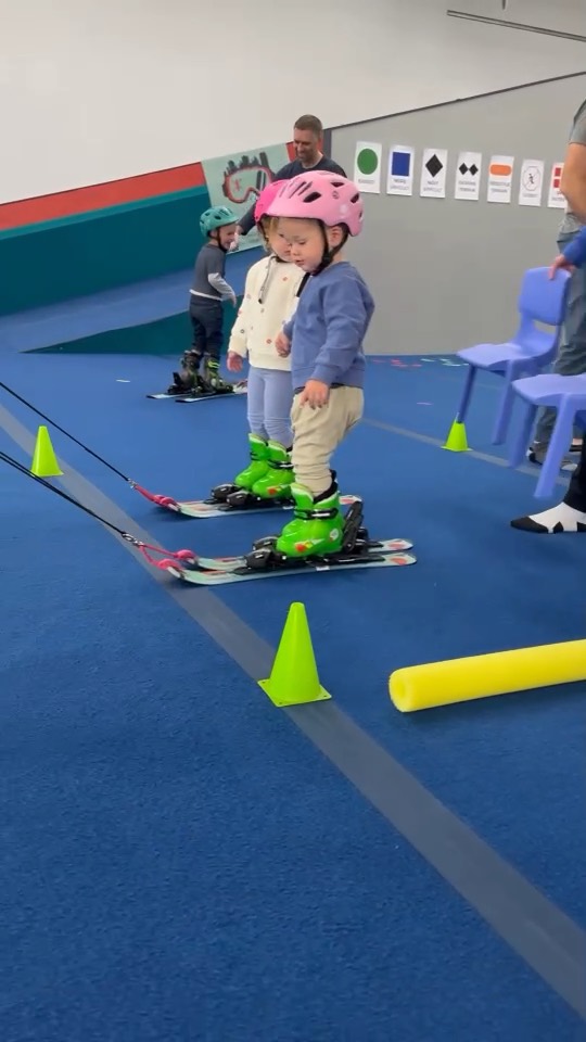 Two toddlers on skis lined up beside a coach at Shredder Livonia