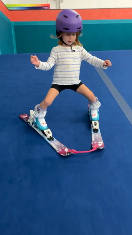 A young skier in a purple helmet skiing down the indoor slope at Shredder Livonia