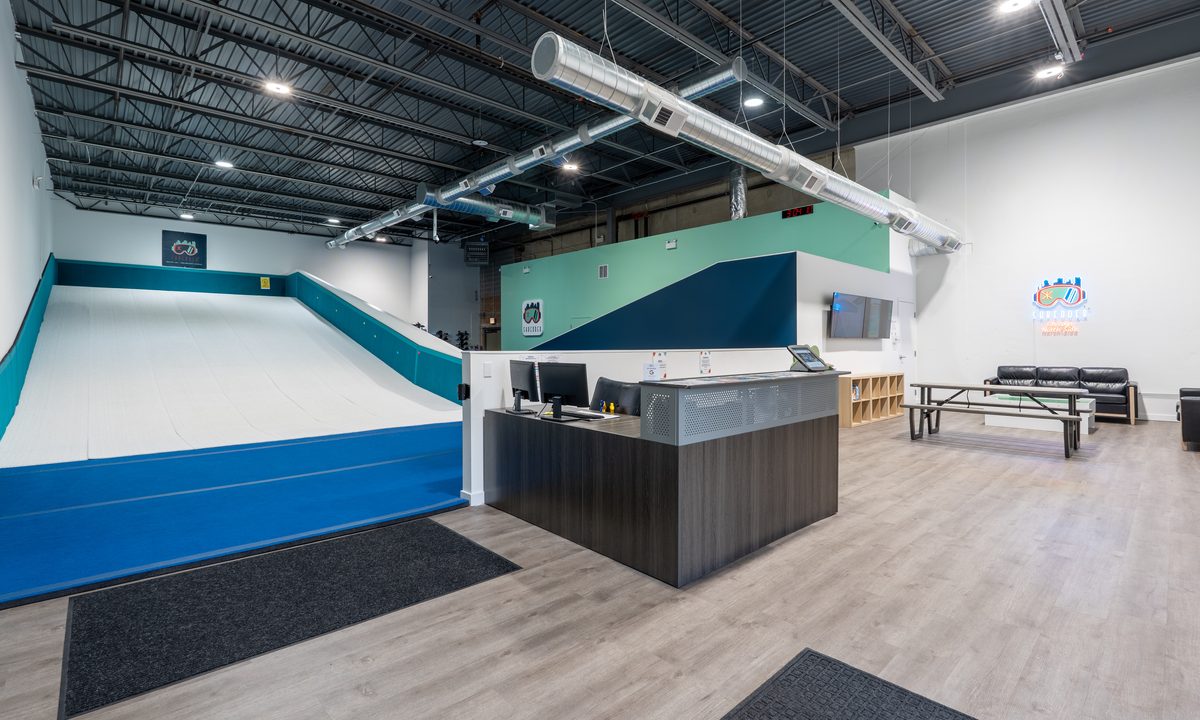 Inside a Shredder facility: check-in desk, a wall of skis and snowboards, and the indoor slope beyond