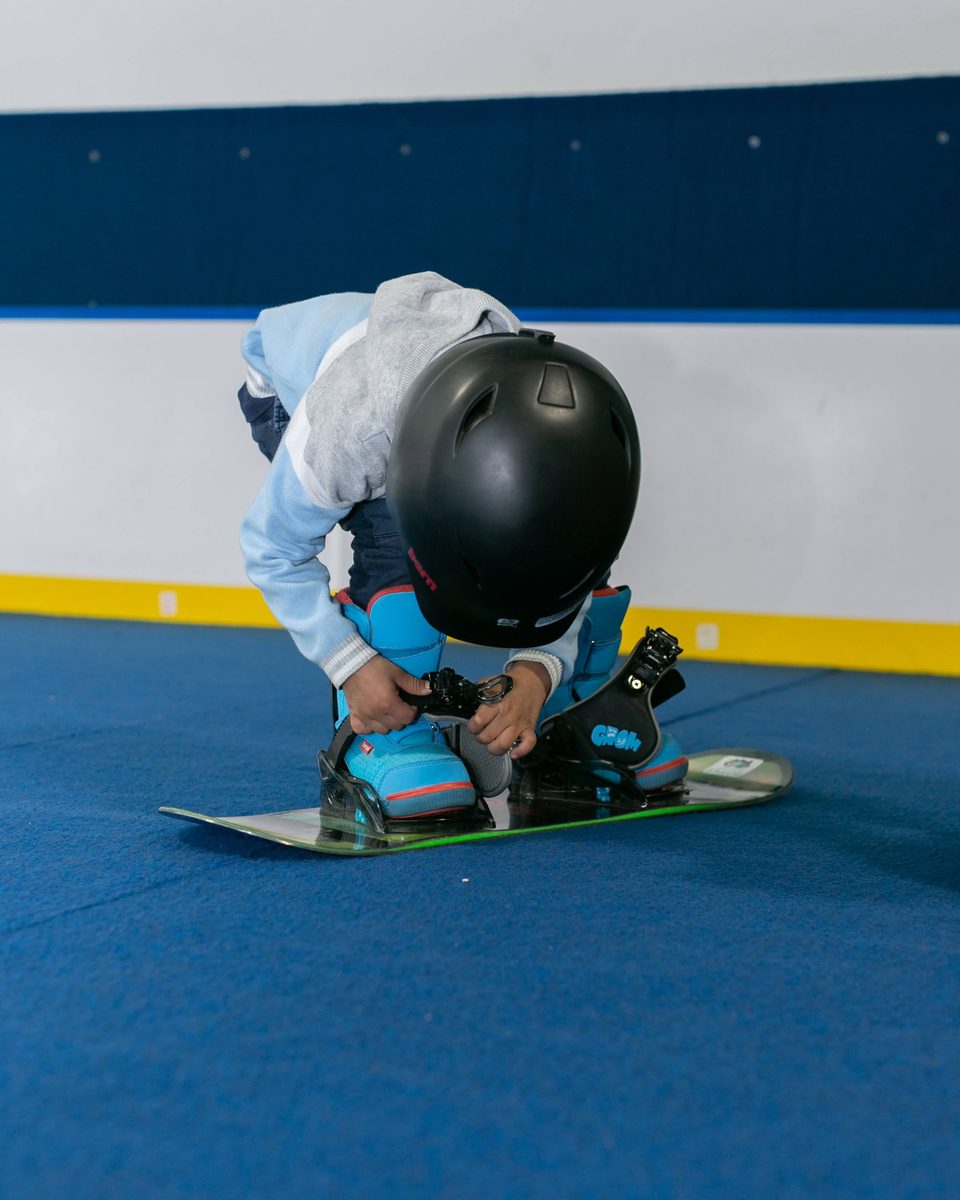 A child buckling their own boot before heading out to the slope