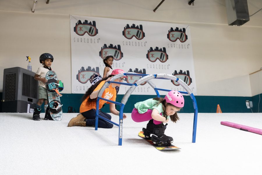 A coach kneeling with one child while others wait their turn