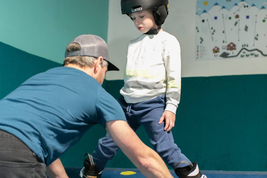 A coach checking a young skier’s boots on the slope