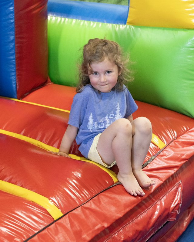 A smiling toddler sitting on a bright red and green inflatable